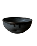 A stack of three handmade ceramic bowls in beige, gray, and purple colors.