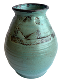 Turquoise ceramic vase with decorative patterns on a white background