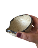 Hand holding a ceramic bowl with a speckled design on a white background