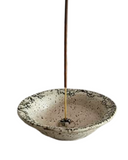 Speckled ceramic incense holder with a gold incense stick on a white background