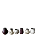 Set of seven ceramic vases with speckled glaze on a white background