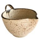Speckled ceramic bowl with a handle on a white background