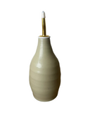 Beige ceramic bottle with a gold cap on a white background