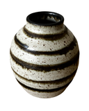 A collection of four ceramic vases, with the Luna Striped Vase in the foreground. The vases are crafted from brown stoneware clay with striped patterns in various shades of bronze.