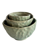 Set of three green ceramic bowls on a white background