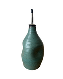 Green ceramic oil bottle with a metallic nozzle on a white background