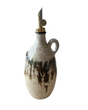 An olive oil pourer and bottle in beige, bronze and gold on a white background. 