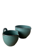 Two teal ceramic bowls on a white background