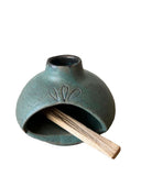A teal palo santo burner on a white background. 