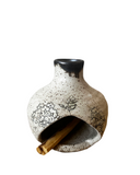 Ceramic palo santo chimney with floral patterns and a cinnamon stick on a white background