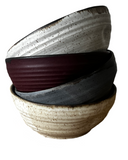 Stack of four ceramic bowls with different textures and colors on a white background