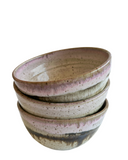 Stack of ceramic bowls with a speckled glaze on a white background