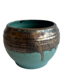 Ceramic pot with turquoise and bronze glaze on a white background