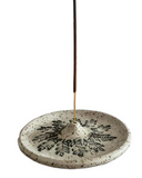 Decorative incense holder with a speckled design on a white background