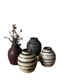 A collection of four ceramic vases, with the Luna Striped Vase in the foreground. The vases are crafted from brown stoneware clay with striped patterns in various shades of bronze.