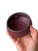 Small red bowl in someone's hand on white background