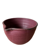 A handcrafted stoneware mixing bowl with a speckled brown and beige color and a bronze lip.