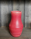 Pink textured vase on a wooden surface with a wooden background