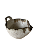 A beige ceramic batter bowl with a speckled pattern and bronze accent at the lip, crafted from brown stoneware clay.