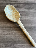 A ceramic spoon on a wooden background