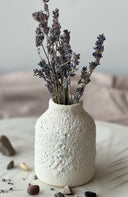 White textured vase with dried lavender on a light surface