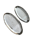 Two oval-shaped ceramic trays with a speckled beige and white glaze finish. One is small and the other is medium-sized.