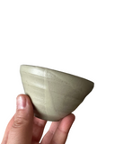 Hand holding a light-colored stone bowl against a white background