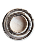 A set of three ceramic plates in a crescent shape with a speckled beige and brown glaze.