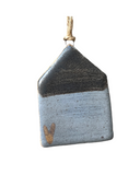 A ceramic house-shaped ornament with a bronze roof and white body, hanging from a twine.