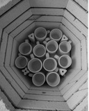 A set of white ceramic cups stacked inside a large, open-structured storage area, possibly a part of a studio or workshop.