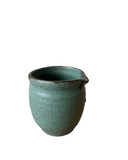 Speckled green ceramic pitcher on a white background