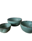 Three teal ceramic bowls of different sizes on a white background