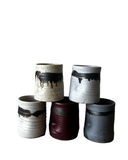 Set of five ceramic pots with unique textures and colors on a white background