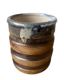 Stoneware pot with ribbed texture and blue and brown glaze on a white background