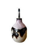Ceramic oil dispenser with black and white speckled design on a white background