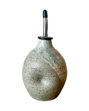 Speckled ceramic oil bottle with a metallic nozzle on a white background