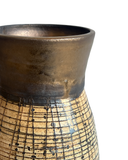 Ceramic vase with textured surface and grid pattern on a white background
