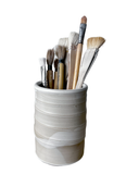 White ceramic cup with paintbrushes on a white background