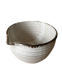 A handcrafted stoneware mixing bowl with a speckled brown and beige color and a bronze lip.