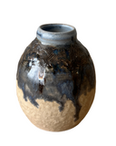 Ceramic vase with textured surface and blue and brown glaze on a white background